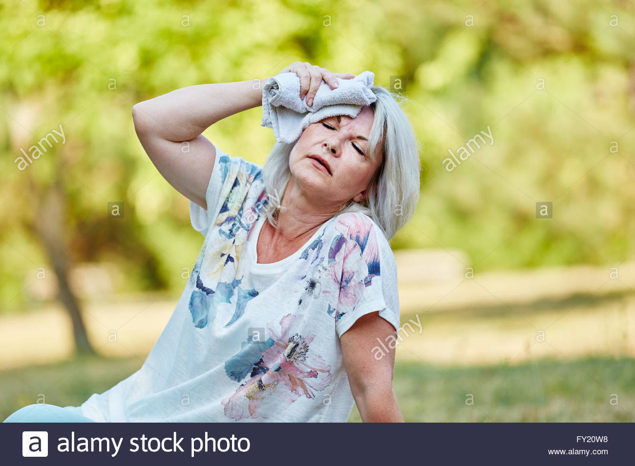 senior-fainting-woman-holds-wet-cloth-on-her-forehead-to-cool-down-FY20W8.jpg